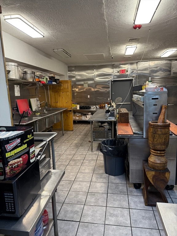 interior space with tile patterned floors, a workshop area, and a textured ceiling