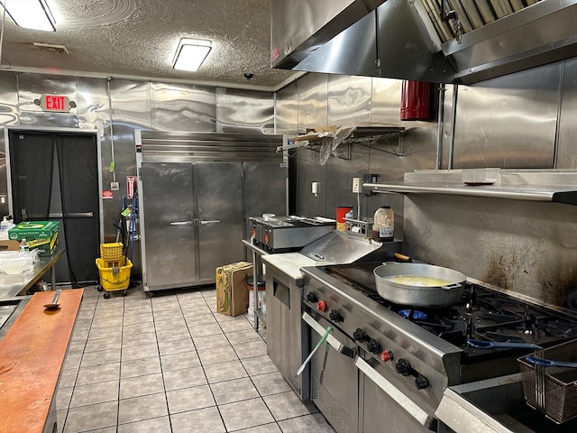 kitchen with light tile patterned floors, a textured ceiling, extractor fan, and high end range