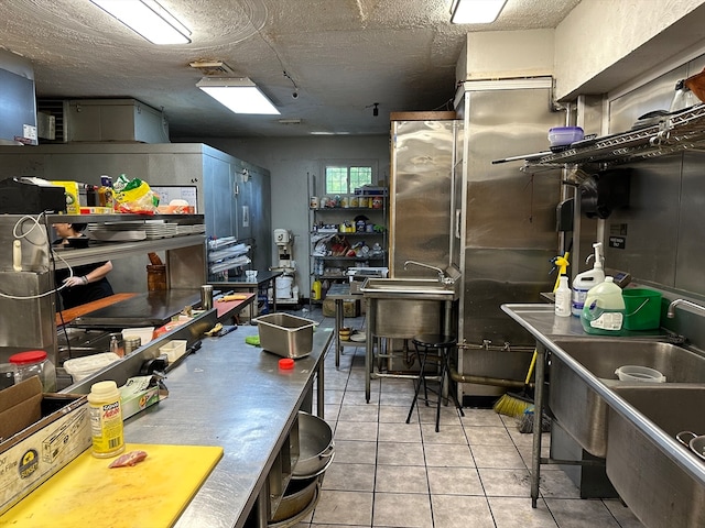 kitchen with sink, light tile patterned floors, and a textured ceiling