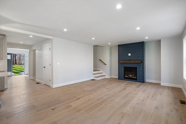 unfurnished living room with a large fireplace and light hardwood / wood-style floors