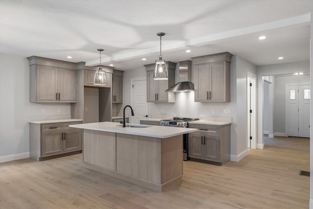 kitchen with light wood-type flooring, sink, wall chimney range hood, stainless steel range oven, and hanging light fixtures