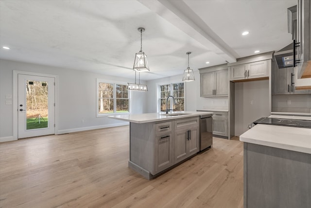 kitchen with pendant lighting, dishwasher, a kitchen island with sink, sink, and light hardwood / wood-style flooring