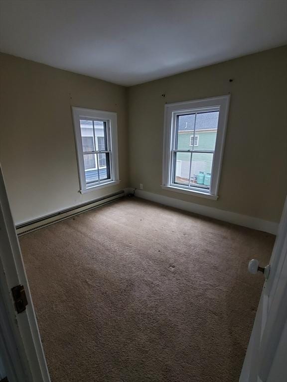 carpeted empty room with a baseboard heating unit