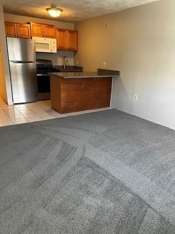 kitchen featuring sink, stainless steel fridge, kitchen peninsula, light colored carpet, and stove