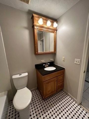 bathroom with vanity, a tub, toilet, and a textured ceiling