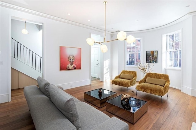 living area featuring crown molding, stairway, wood finished floors, and baseboards