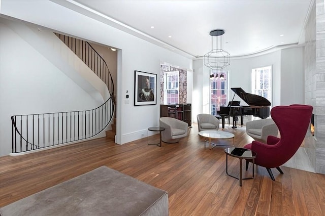 living area with stairs, baseboards, wood finished floors, and an inviting chandelier