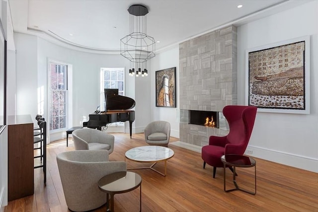 living area featuring a notable chandelier, a fireplace, recessed lighting, wood finished floors, and baseboards