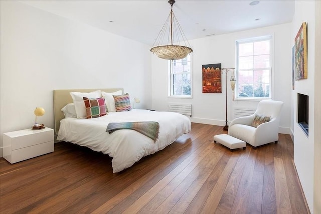 bedroom with a fireplace, wood finished floors, and baseboards