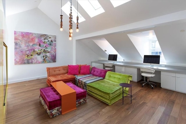 living area with lofted ceiling with skylight, wood finished floors, built in study area, and baseboards