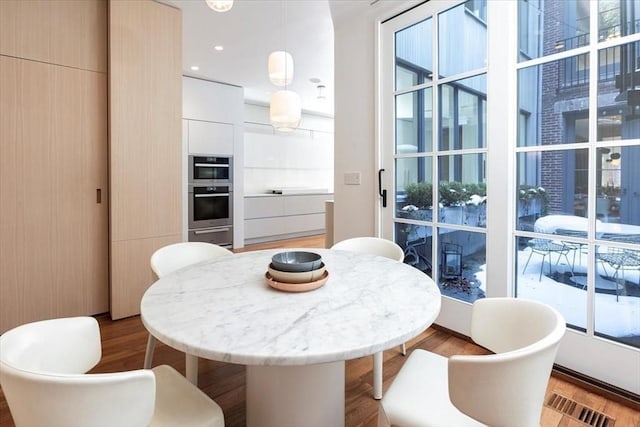 dining area with plenty of natural light, visible vents, and wood finished floors