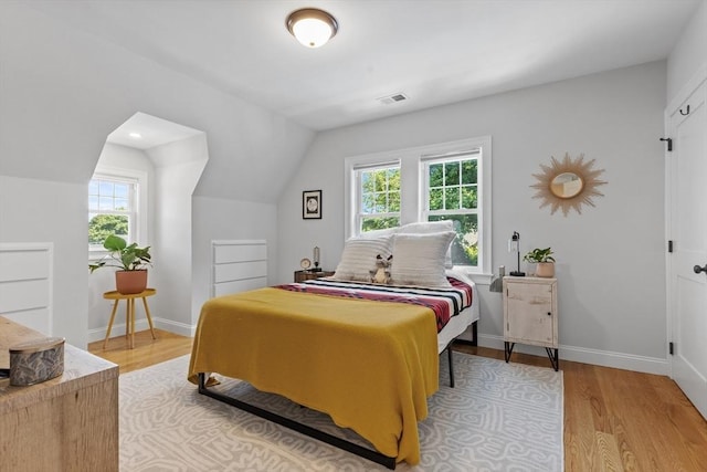 bedroom with light hardwood / wood-style floors and lofted ceiling