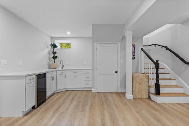 kitchen featuring white cabinets, dishwasher, light hardwood / wood-style floors, and sink