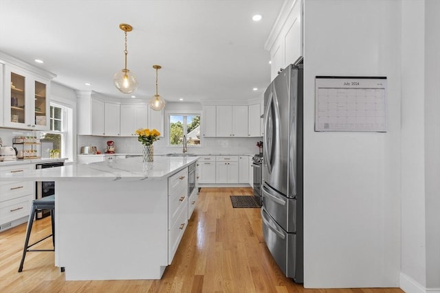 kitchen with tasteful backsplash, white cabinetry, a kitchen bar, a center island, and stainless steel appliances