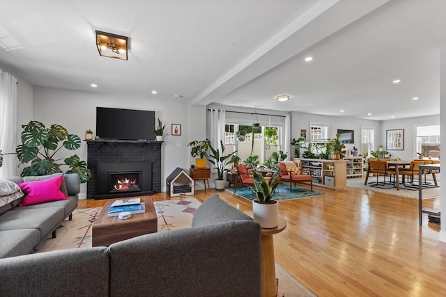 living room with a brick fireplace and light wood-type flooring