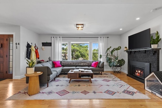 living room with a brick fireplace and light hardwood / wood-style flooring