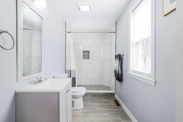 bathroom with visible vents, baseboards, tiled shower, toilet, and vanity