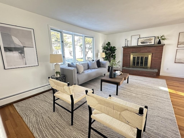 living room with a baseboard heating unit, a brick fireplace, and hardwood / wood-style flooring