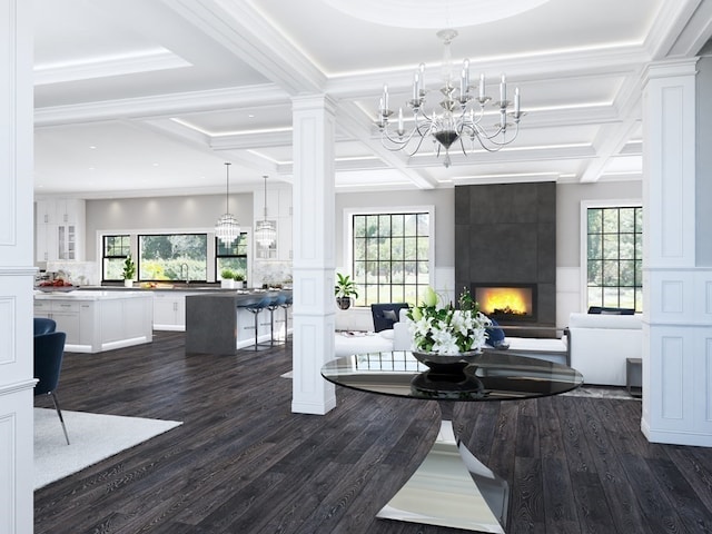 living room featuring dark wood-type flooring, a notable chandelier, coffered ceiling, a wealth of natural light, and a tiled fireplace