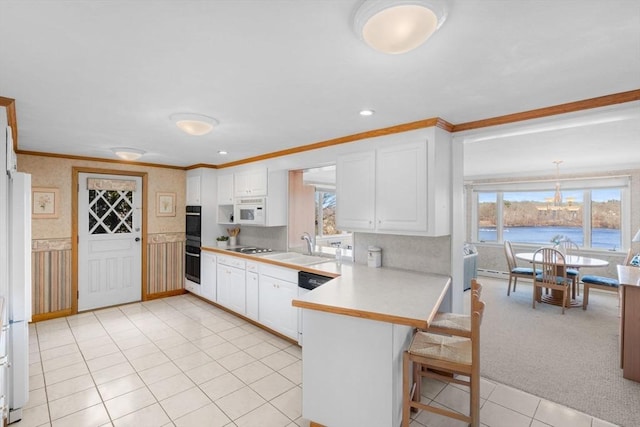 kitchen with black appliances, ornamental molding, a kitchen breakfast bar, a peninsula, and light countertops