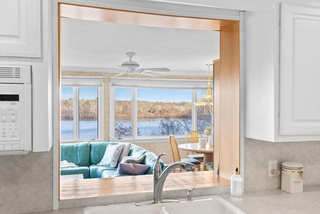 details with a ceiling fan, white microwave, a sink, light countertops, and white cabinetry