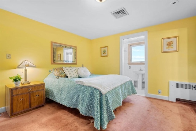 bedroom featuring visible vents, baseboards, radiator heating unit, light colored carpet, and connected bathroom