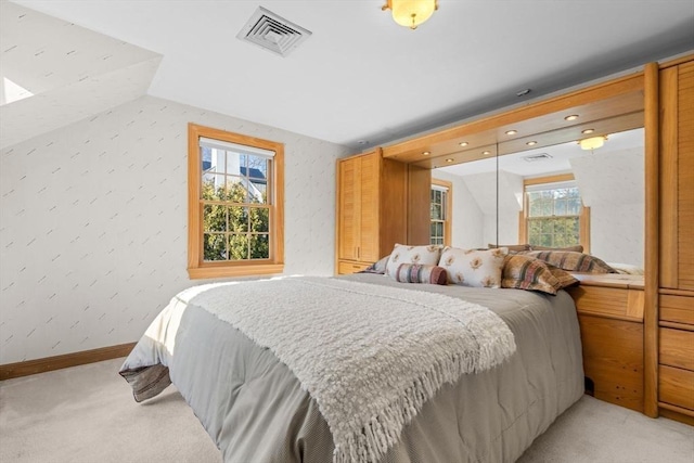 bedroom with visible vents, lofted ceiling, light colored carpet, and baseboards