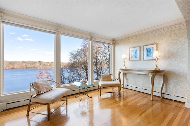 sitting room with ornamental molding, a textured ceiling, a water view, and wood finished floors