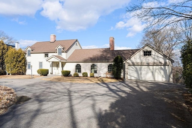 view of front facade with aphalt driveway, a garage, and a chimney