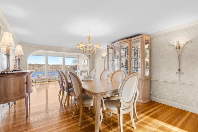 dining area with wallpapered walls, crown molding, baseboards, light wood-style floors, and a notable chandelier