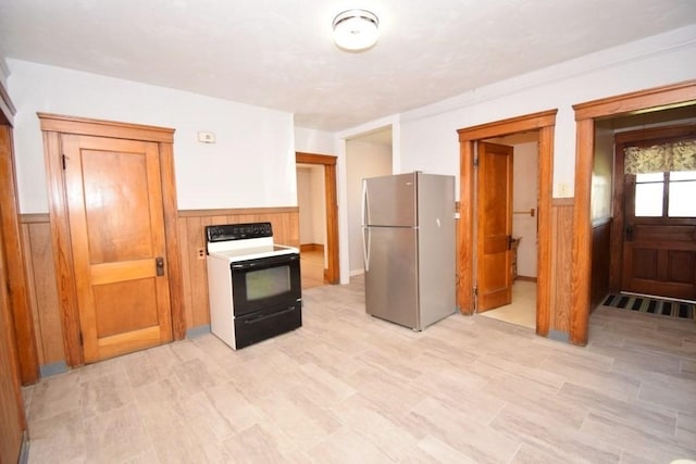 kitchen with freestanding refrigerator, electric range, a wainscoted wall, and wood walls