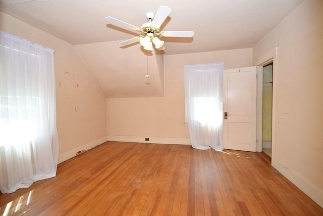 additional living space featuring baseboards, a ceiling fan, vaulted ceiling, and light wood-style flooring