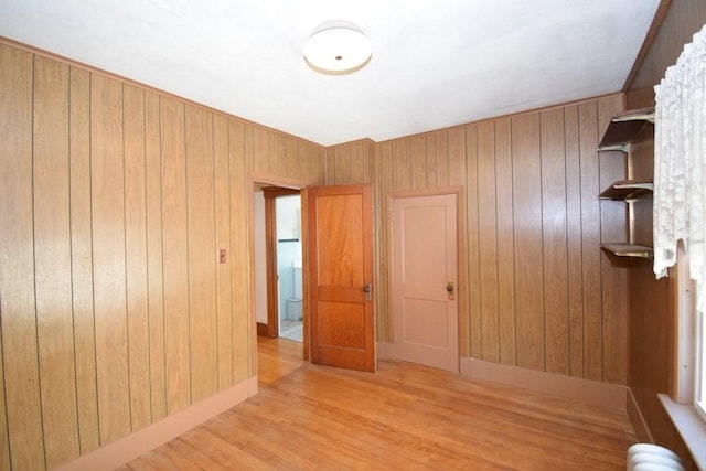 empty room with baseboards, wood finished floors, and wooden walls