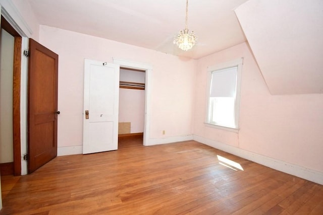 unfurnished bedroom featuring baseboards, light wood-style flooring, and a chandelier
