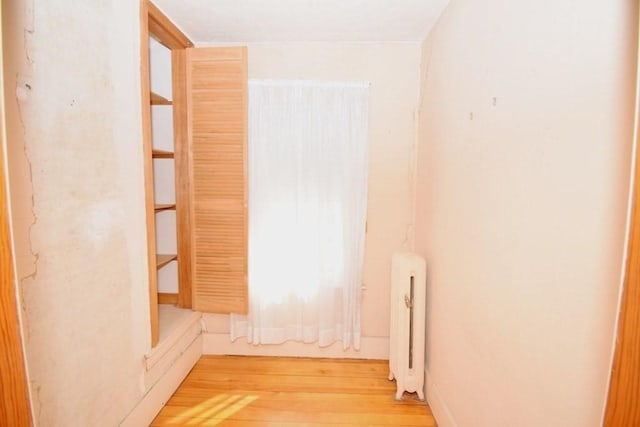 unfurnished room featuring radiator heating unit and light wood finished floors