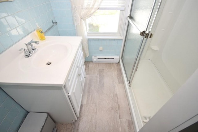 full bathroom featuring vanity, tile walls, baseboard heating, tile patterned floors, and a stall shower