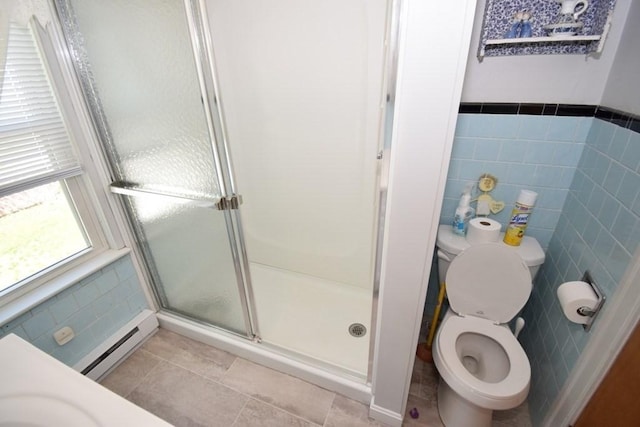 bathroom featuring toilet, tile walls, baseboard heating, tile patterned floors, and a shower stall