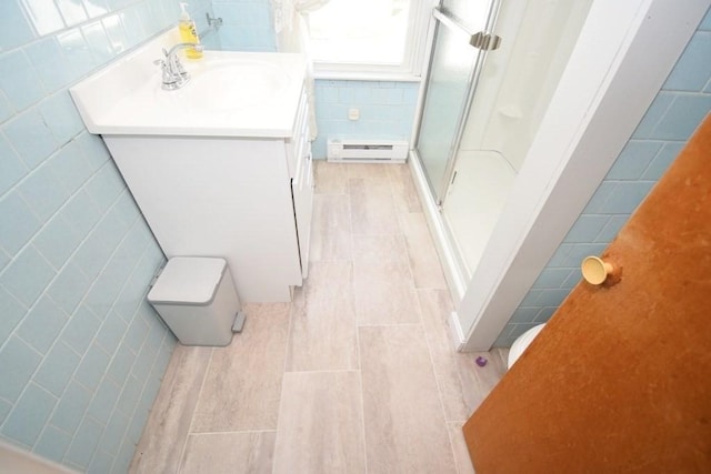 bathroom with vanity, tile patterned flooring, tile walls, a baseboard heating unit, and a stall shower