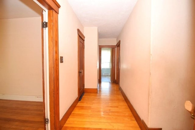 corridor with baseboards and light wood finished floors