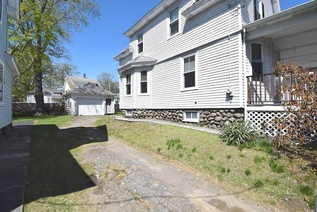 view of side of home featuring a detached garage, an outbuilding, and a yard