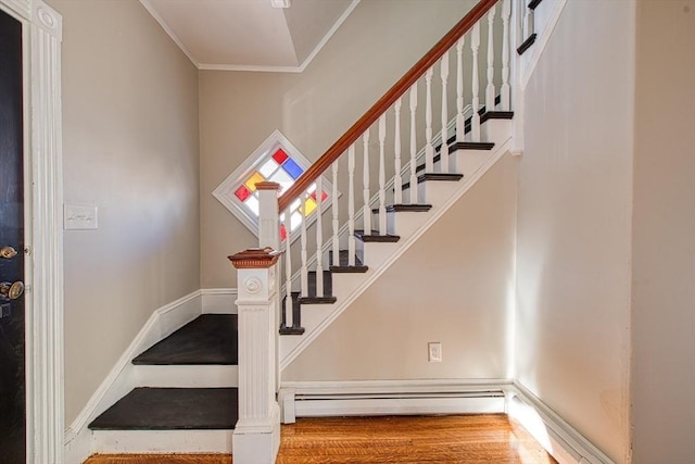 stairs with hardwood / wood-style floors, baseboard heating, and ornamental molding