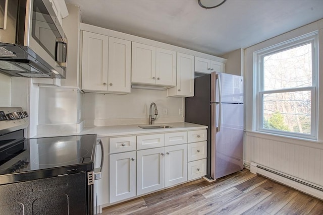 kitchen with plenty of natural light, baseboard heating, sink, and stainless steel appliances