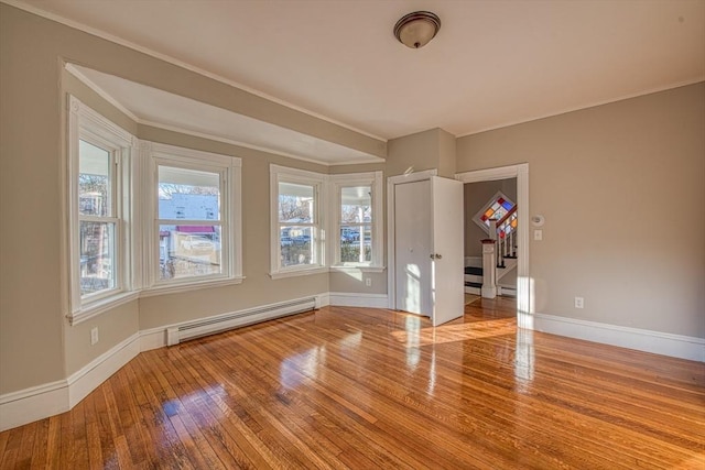 unfurnished room featuring light hardwood / wood-style flooring, a baseboard heating unit, and crown molding