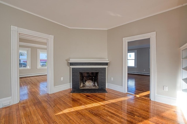 unfurnished living room featuring a brick fireplace, hardwood / wood-style floors, ornamental molding, and a baseboard heating unit