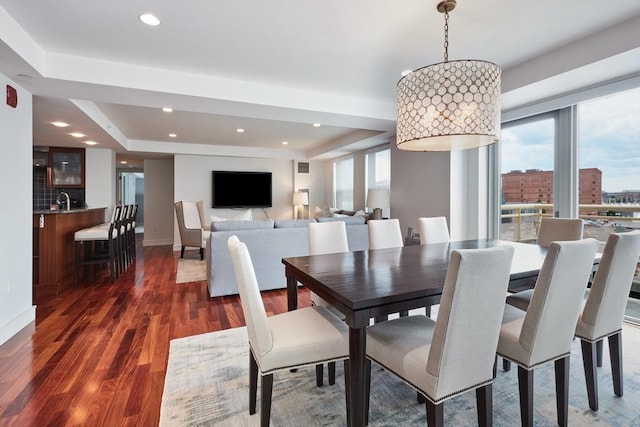 dining area featuring dark hardwood / wood-style flooring, a tray ceiling, and plenty of natural light