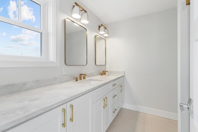 bathroom with double vanity, baseboards, and a sink