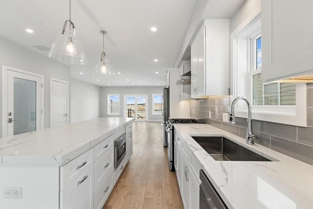 kitchen with a sink, a center island, recessed lighting, stainless steel appliances, and light wood-style floors