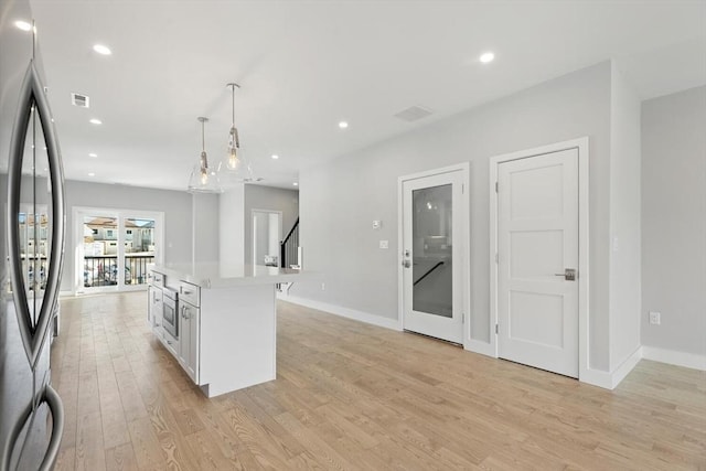 kitchen featuring light wood-type flooring, light countertops, recessed lighting, stainless steel refrigerator, and white cabinets