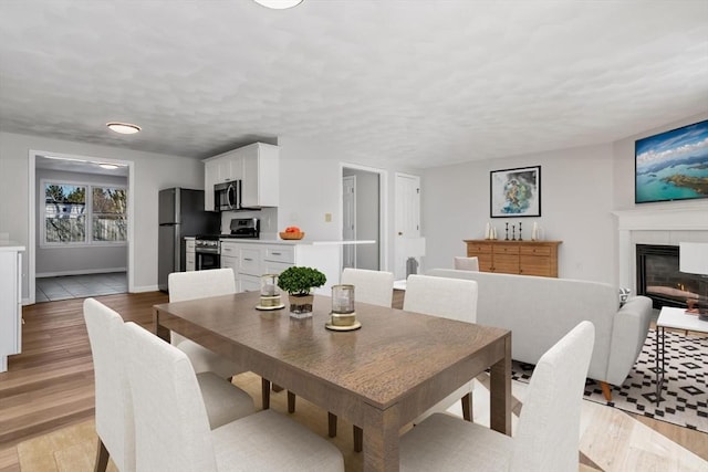 dining area featuring light hardwood / wood-style floors and a tile fireplace