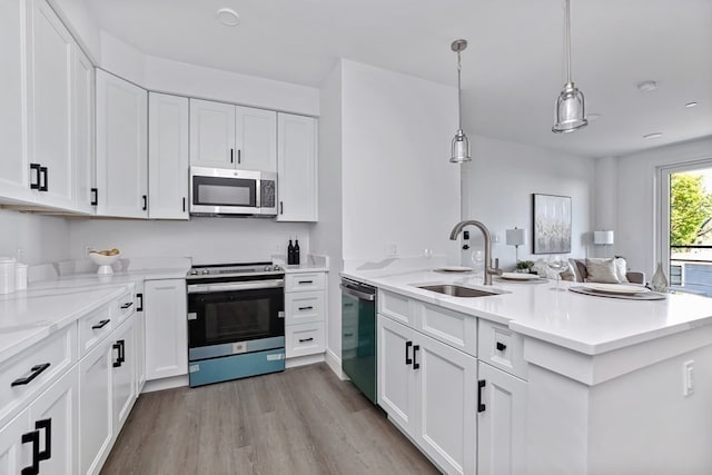 kitchen featuring white cabinets, kitchen peninsula, sink, decorative light fixtures, and stainless steel appliances